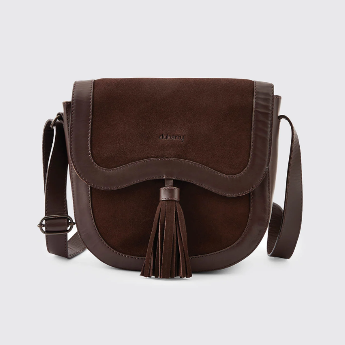 Dubarry Of Ireland Monart Bag Variant Cigar. A dark brown suede and leather crossbody bag with a tassel detail and a small 'DUBARRY' logo on the front, set against a light gray background.