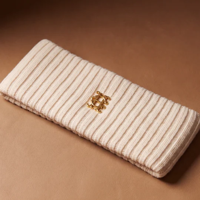 A cream-colored ribbed headband with a Gold HC logo on a Brown background.