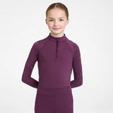 Young girl wearing a Plum base layer with crystal embellishments on the shoulder against a grey background. 