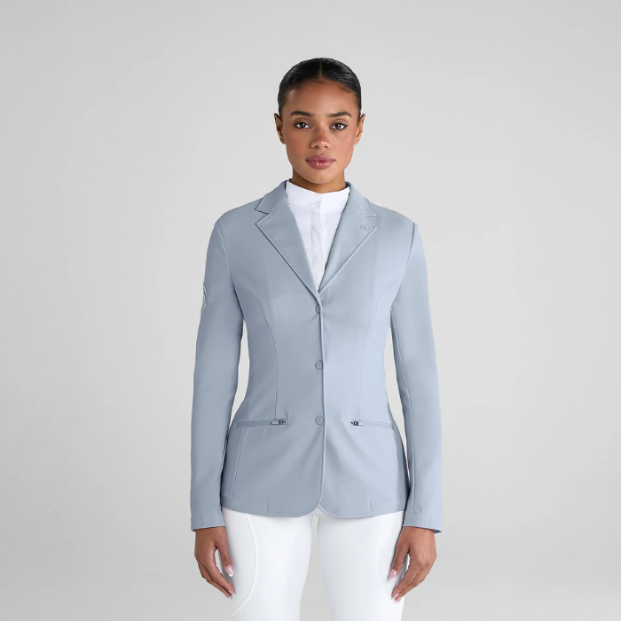 Person wearing ash blue jacket with white trousers on grey back ground