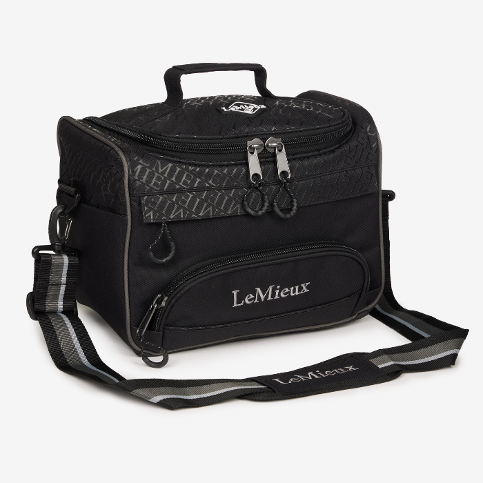LeMieux AW26 Elite ProKit Lite Grooming Bag Varient Black. A black LeMieux horse tack storage bag with a top handle, front zippered pocket, and an adjustable shoulder strap, shown on a light grey background.