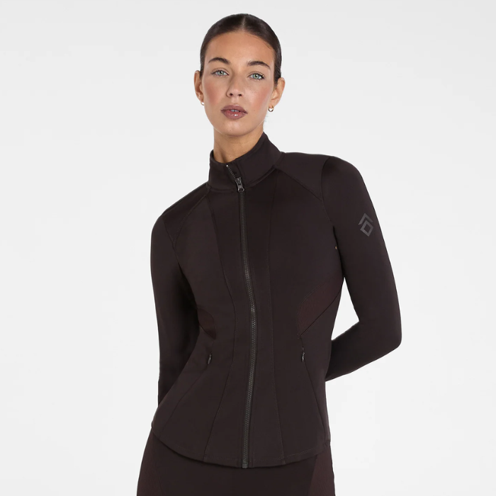 Aztec Diamond AW26 Core Fitted Jacket Variant Espresso. A woman modeling a dark brown full-zip athletic jacket with a mock neck and long sleeves, featuring a subtle logo on the left sleeve, against a plain white studio background.