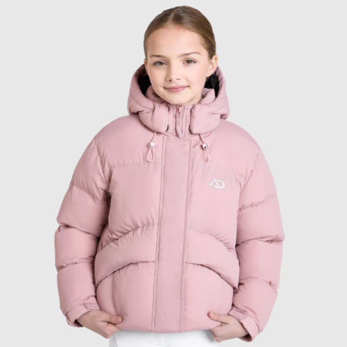 Young girl wearing a pink puffer jacket on a light grey background