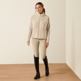 Ariat Yth Laviolette Full Zip Vest Varient Almond Milk. Lady wearing a cream fleece gilet with matching beige trousers on a light background.