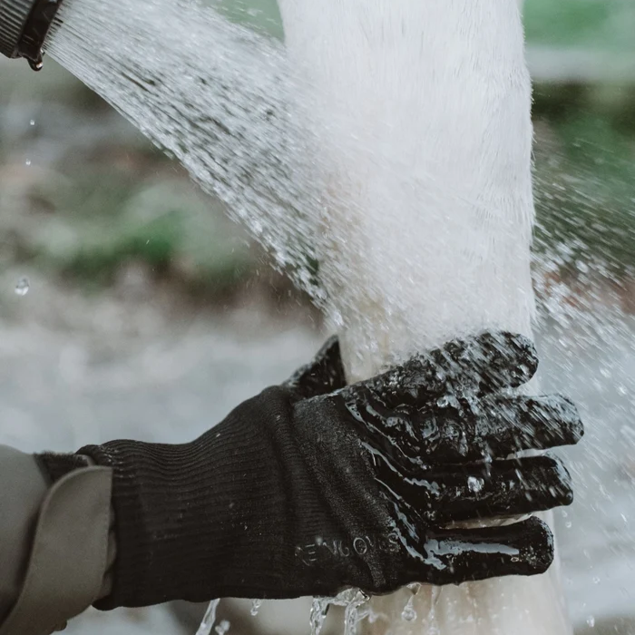 A black glove placed on a horses leg under gushing water. 