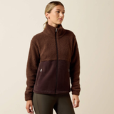 Ariat Ladies Laviolette Full Zip Jacket Variant Chocolate Plum. A woman wearing a brown and dark plum fleece zip-up jacket, paired with dark gray leggings, standing against a plain beige studio background.