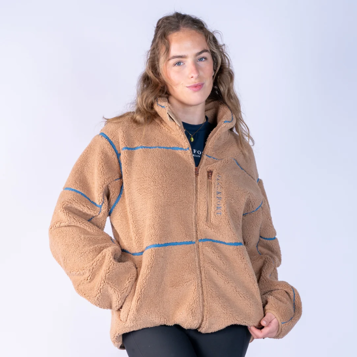 Blackfort AW26 Layla Fleece Variant Tan & Glacier. Tan fleece with blue lin detailing and a blue 'BLACKFORT' logo against a grey background. 