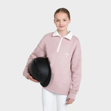 Person wearing a pink equestrian shirt holding a black helmet on a white background