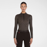 A model wearing a dark brown and black patterned long-sleeve half-zip riding shirt with a matching patterned riding belt, paired with black riding pants, against a plain white studio background.