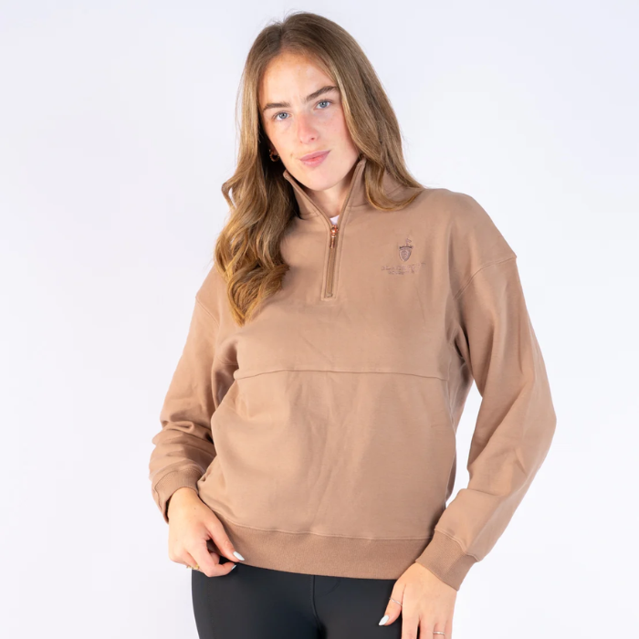 Blackfort Equestrian Ella Quarter Zip Variant Caramel. A woman modeling a light brown quarter-zip sweatshirt with a small embroidered logo on the left chest, paired with black pants, against a plain white studio background.