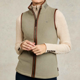 Holland Cooper Country Fleece Gilet Variant Sage. Woman wearing a Sage gilet with brown rim detailing and a small HC logo over a cream jumper on a grey background.