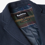 Close-up of a navy wool-blend coat lapel and collar with a Barbour plaid inner lining and visible Barbour branding label.