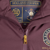 Close-up of a Holland Cooper zip-up jacket in maroon, showing the gold zipper, interior neck label with crest details, and part of the embroidered chest logo.