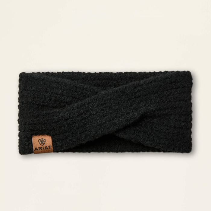 Ariat Ladies Chilton Headband Variat Black. A black textured knit twist-front ear warmer with a small brown leather ARIAT brand tab on the lower left, displayed flat against a light cream background.