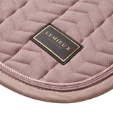 A close-up of a dusty rose quilted textile pad with a black and gold Lemieux Heritage label, showing the chevron stitching and braided edge.