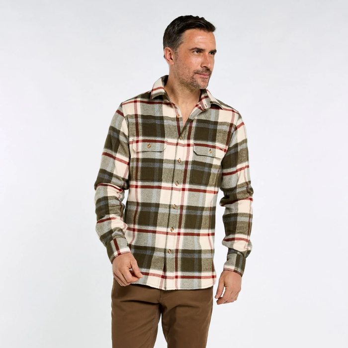 Dubarry Townley Men's Hunting Check Shirt Variant Dusky Green. A man wearing a long-sleeve plaid flannel shirt in olive green, beige, and red, paired with brown pants, standing against a light gray studio background.