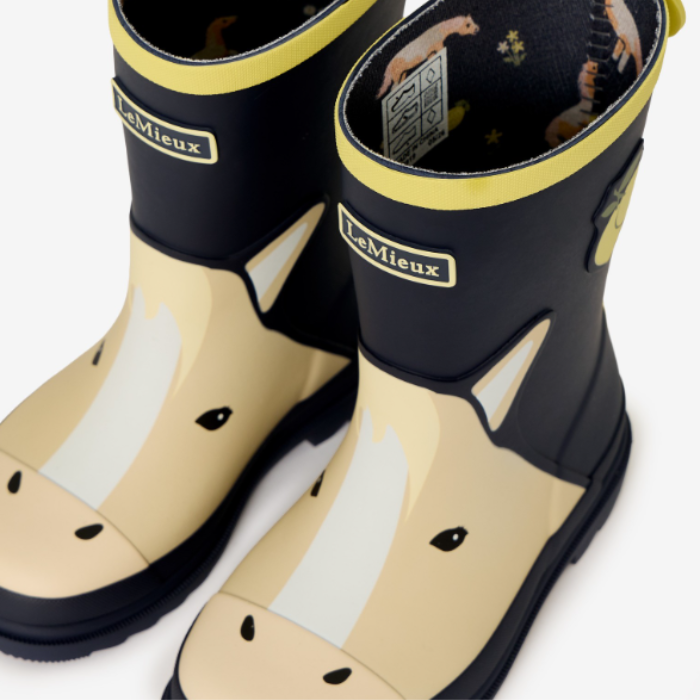 LeMieux AW26 Splash Welly Varient Lemon. A pair of LeMieux children's rain boots featuring a beige and white horse face design on the lower half, a black upper, and yellow trim, shown on a clean white background.