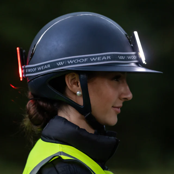 Person wearing a Woof Wear helmet and high-visibility jacket in a dark setting