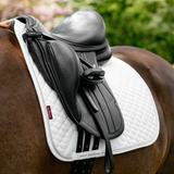 Black saddle on a horse with a white saddle pad, brand 'LeMieux' visible.