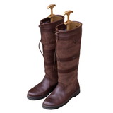 Pair of brown riding boots with gold boot tree's on a white background. 