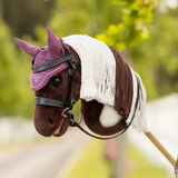 Toy horse head with bridle and pink ear hood on faded woodland background