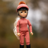 LeMieux AW26 Toy Rider Amelia Varient Multi. Blonde toy rider wearing a matching spiced outfit and black boots with a matching riding hat against a blurred background. 