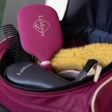 LeMieux AW26 ProKit Lite Grooming Bag Varient Blackberry. A close-up of a pink and navy blue LeMieux travel hair care set inside a burgundy zippered bag, including a pink paddle brush, a black comb, and a yellow brush.