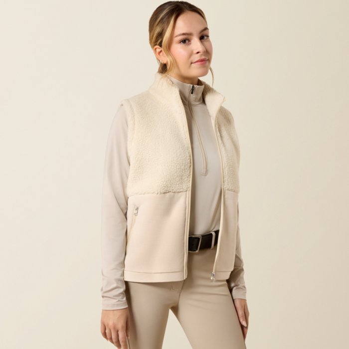 Ariat Yth Laviolette Full Zip Vest Varient Almond Milk. Lady wearing a cream fleece gilet with matching beige trousers on a light background.