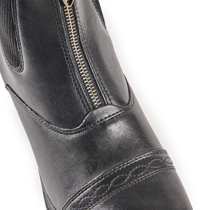 Close-up of a black leather boot with a gold zipper on a white background