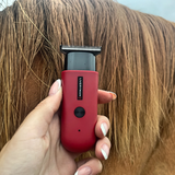 Red hair trimmer being used on a person's head with visible Liveryman branding.