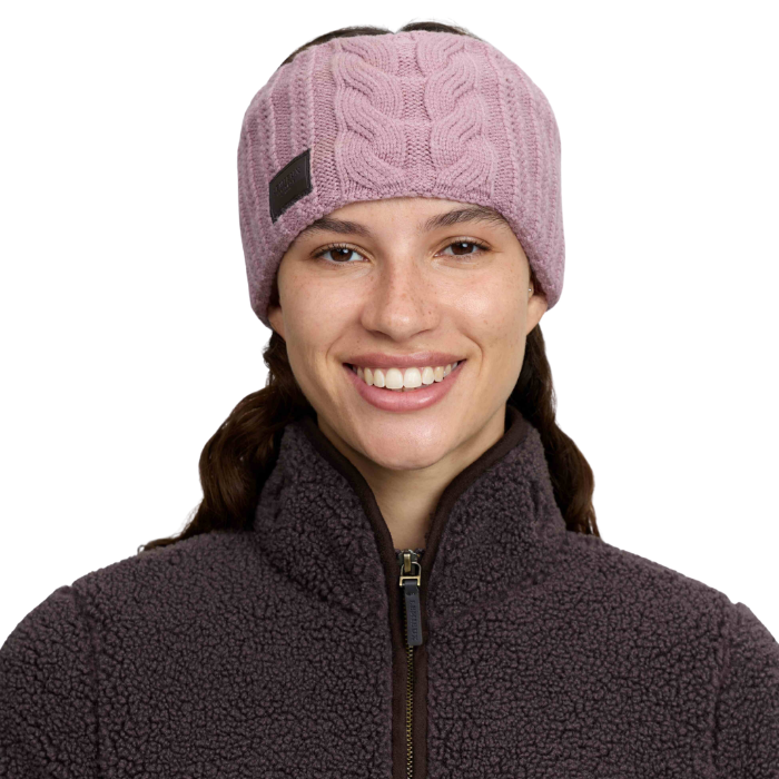 Woman wearing a pink headband with brown logo against a white background. 