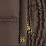 Holland Cooper Cranborne Training Gilet Variant Chocolate. Close-up detail of a brown quilted jacket showing a gold-tone zipper pull and a matching gold-tone crest logo charm.