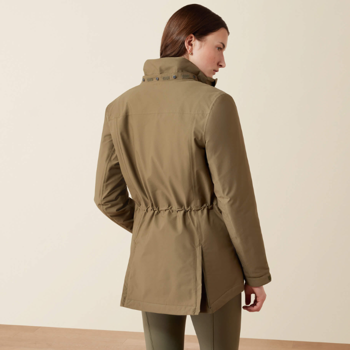 Back of woman wearing a olive jacket with adjustable sinched in waist against a beige background.