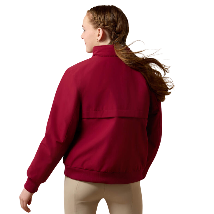 Ariat Youth 2.0 Insulated Stable Jacket Variant Beet Red. A woman shown from the back wearing a burgundy zip-up jacket and beige pants against a plain white background.