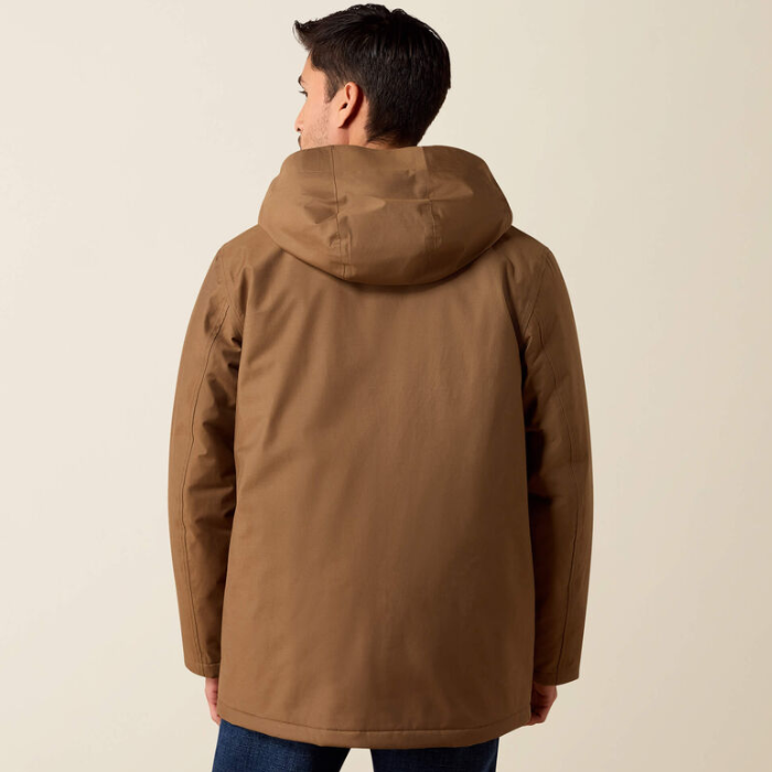 A man viewed from the back wearing a brown hooded jacket, paired with blue jeans, against a plain light beige studio background.