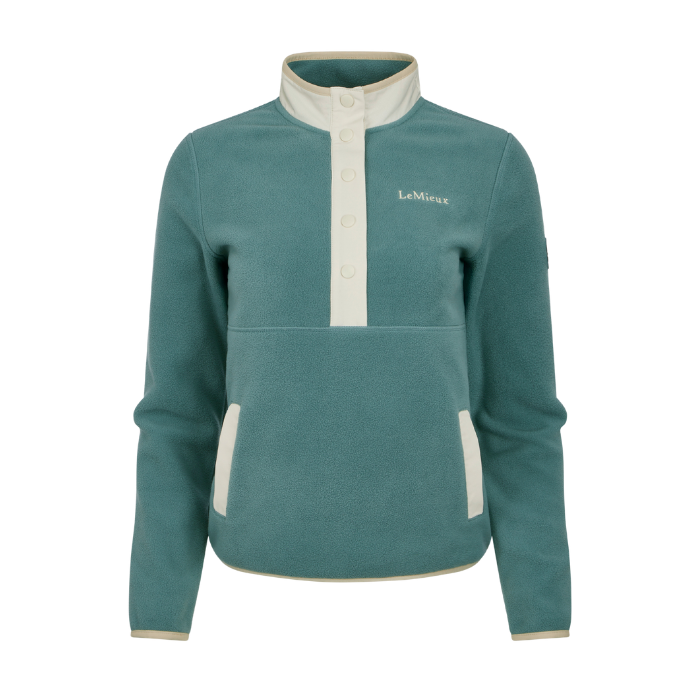 LeMieux AW26 Piper Popper Fleece Varient Aloe. A teal fleece pullover jacket with cream-colored trim on the stand-up collar, button placket, and side pockets, featuring the 'LeMieux' brand name embroidered on the left chest.