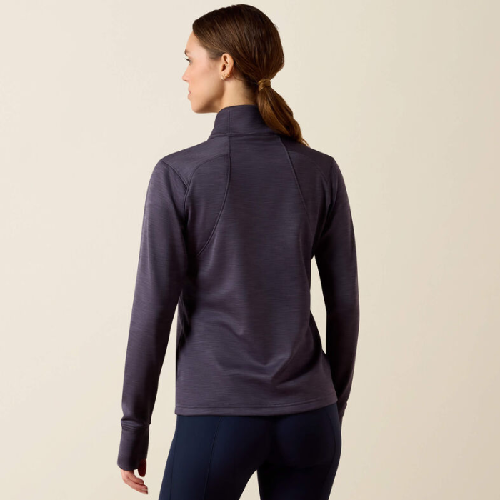 Ariat Ladies Team EQ 1/2 Zip Pullover Variant Odyssey Grey. A woman shown from the back wearing a dark heathered purple athletic quarter-zip pullover and dark leggings, set against a plain light beige studio background.