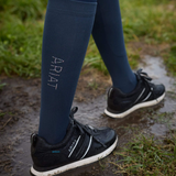 Person wearing Ariat socks with navy trainers walking through a puddle. 