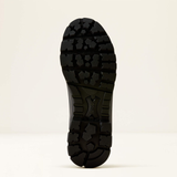A close-up of a black rubber boot sole, showing its deep tread pattern, photographed against a clean off-white background.
