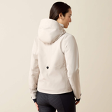 A woman shown from the back wearing a light cream hooded jacket and dark patterned leggings against a plain beige studio background.