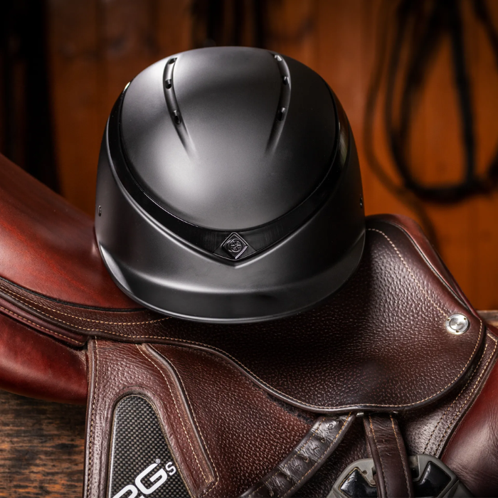 Charles Owen Luna Riding Hat placed on a saddle
