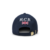 Holland Cooper HC Equestrian Cap Variant Ink Navy. Back of a navy cap with 'H.C.E' and a GB flag printed on the back with a gold adjustble strap buckle. 