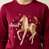 Ariat Yth Painted Dream Long Sleeve T-Shirt Varient Beet Red. Close up of red long sleeve top with horse graphic involving stars and hearts and Ariat branding. 