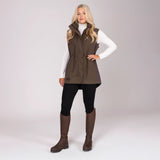Woman wearing a brown gilet, white shirt, black leggings, and brown boots on a white background