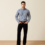 Ariat Men's Clement Long Sleeve Shirt Varient Soft Blue Plaid. A man wearing a light blue and grey plaid button-down shirt, black pants, and a brown belt, standing against a plain beige studio background.