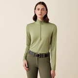Ariat Ladies Lunaveil 1/2 Zip Long Sleeve Base Layer Variant Oil Green. Woman wearing a 1/2 zip green baselayer against a beige background. 