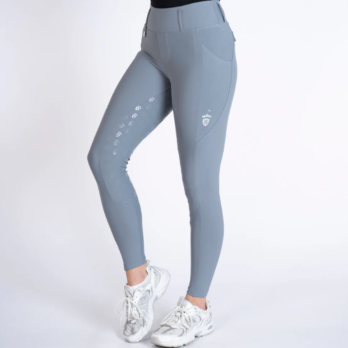 A person wearing high-waisted gray athletic leggings with white sneakers, shown from the waist down against a plain light gray studio background.