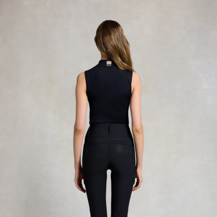 Person wearing a black sleeveless top and pants with a visible brand logo on a neutral background