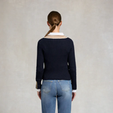 Person wearing a navy sweater with a striped collar and blue jeans on a plain background. Holland Cooper Zoe Knit Jumper Navy