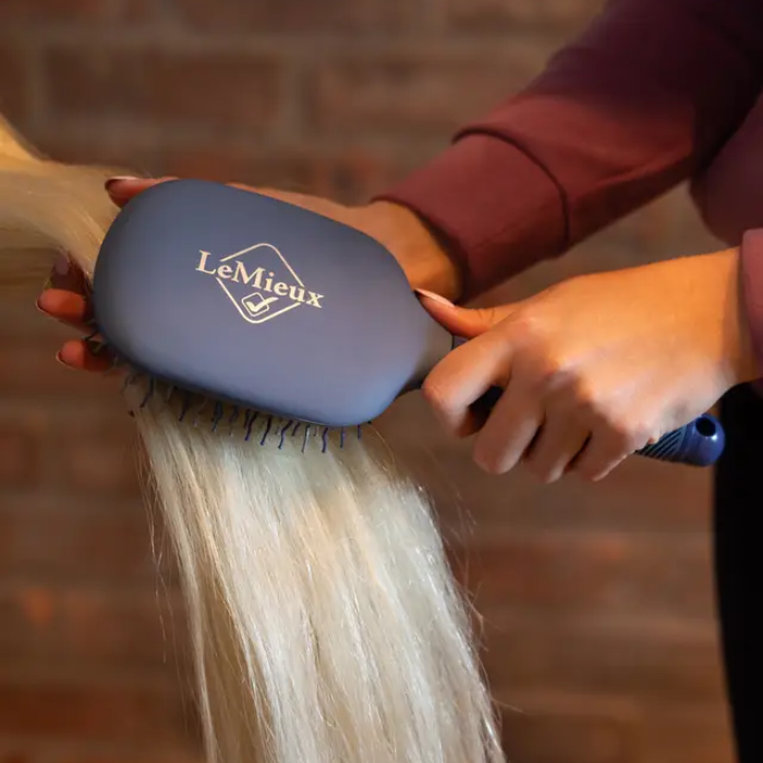 Person using a brush 'LeMieux' on a faded background